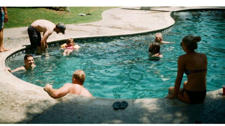 family and friends swimming in an inground pool